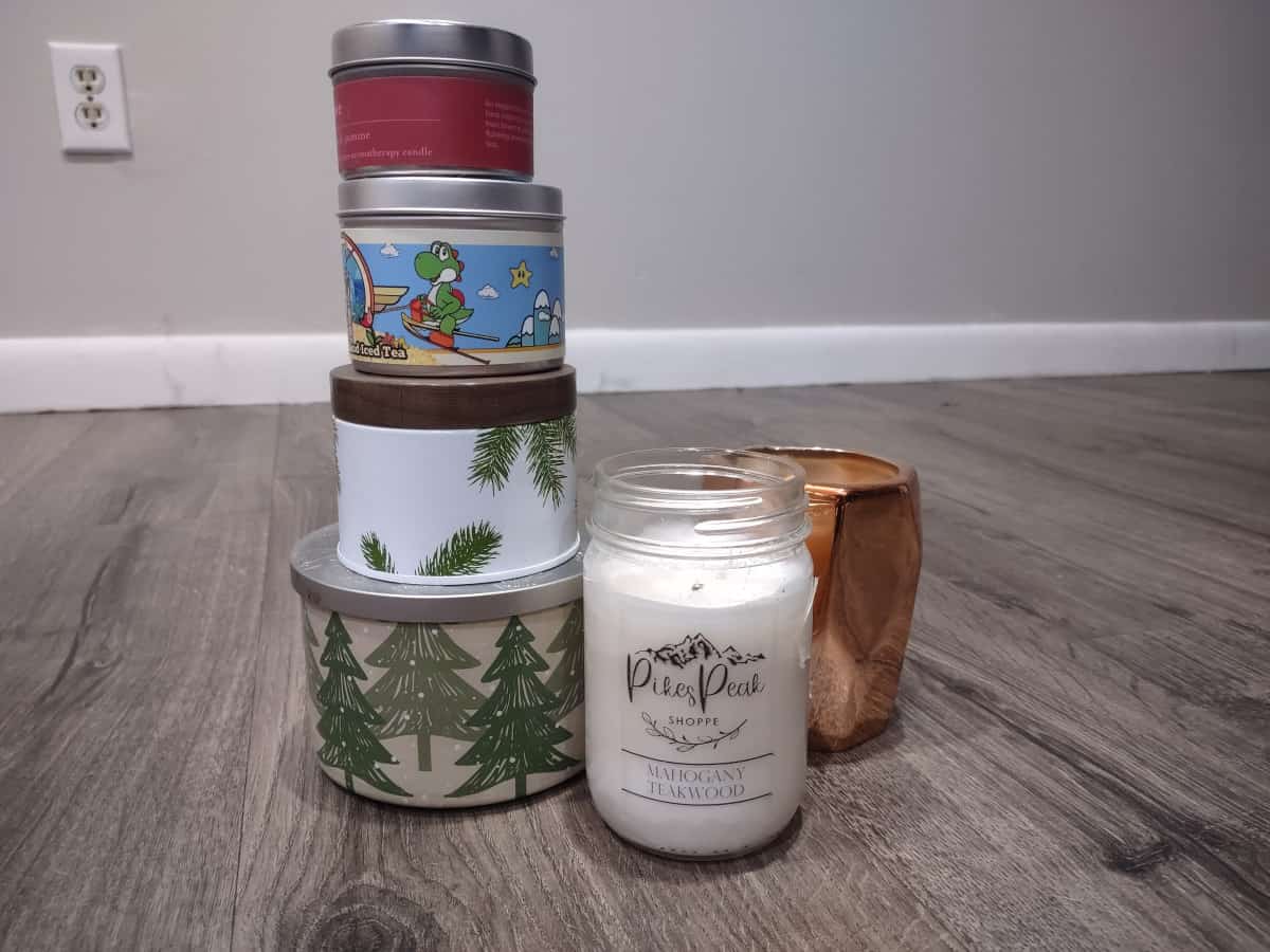Six candle jars on the floor with four of the tin candle jars stacked on top of each other