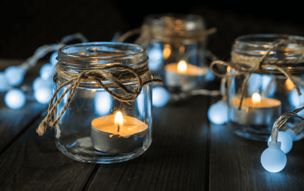 Three glass candle jars with lit tea lights inside